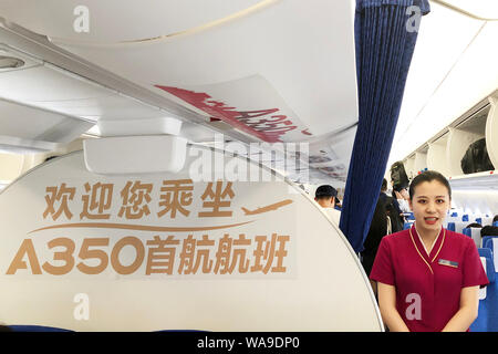 Un assistente di volo serve i passeggeri in classe economica per il primo Airbus A350-900 aereo jet dotata della nuova sede di prodotti di China Southern Airlin Foto Stock