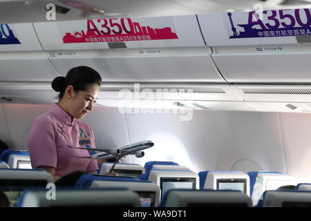 Un assistente di volo serve i passeggeri in classe economica per il primo Airbus A350-900 aereo jet dotata della nuova sede di prodotti di China Southern Airlin Foto Stock