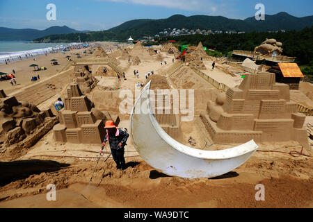 Lavoratori cinesi per intagliare le sculture di sabbia con forma di personaggi dei cartoni animati per la scultura di sabbia Festival di Nansha punto panoramico in Zhoushan city Foto Stock