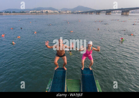 I residenti locali raccogliere e tuffarsi nel fiume Han raffreddare su un bruciante giorno in Xiangyang city, centrale cinese della provincia di Hubei, 22 luglio 2019. Foto Stock