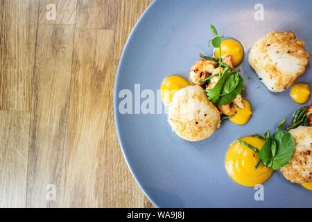 Colpo di pollo con gamberi e foglie di verdure una piastra rotonda blu Foto Stock