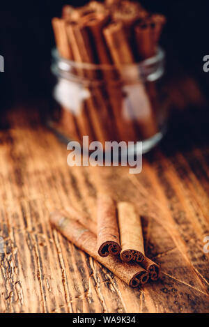 Bastoncini di cannella in un vasetto di vetro su rustico superficie in legno Foto Stock