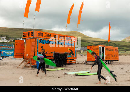I giovani surfisti della Offshore Surf School noleggiano una cabina arancione come surf in Irlanda a Inch Beach, nella contea di Kerry, Irlanda Foto Stock
