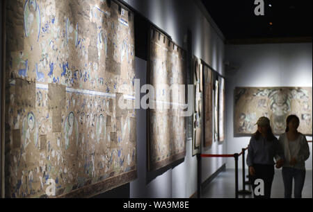 --FILE--i visitatori visualizzazione di una raccolta fotografica dei dipinti sulle pareti delle grotte Kizil conservati all'estero presso un museo in Luoyang city, centrale della Cina di Henan pr Foto Stock