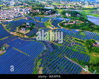 --FILE--Vista aerea di schiere di pannelli solari installati sulle montagne e sul tetto degli edifici nel villaggio di Changjiang, Zhoutian town, Hui Foto Stock