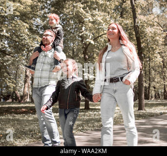 La famiglia gode di una passeggiata nel parco della città. Foto Stock