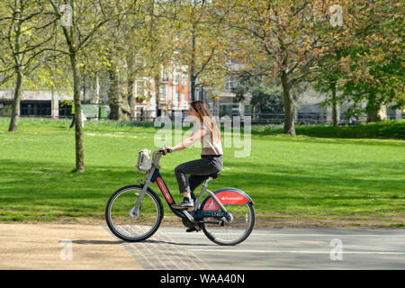Giovane donna cavallo noleggiato in bicicletta in Hyde Park, London, Regno Unito Foto Stock