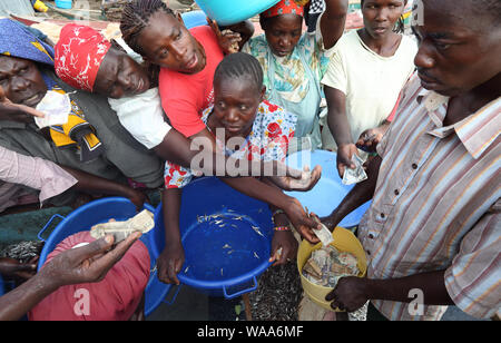 I pescatori e le donne sul mercato del pesce del commercio in un tradizionale villaggio di pescatori del Lago Vittoria, Kenya Foto Stock