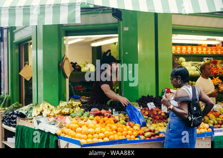 London / UK - Luglio 16, 2019: donna acquisto di frutti alla Brixton Mercato alimentare di stallo, che offrono diversi tipi di frutta e verdura Foto Stock