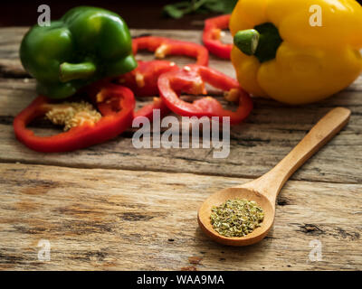 Chiudere il cucchiaio di legno con utensili erbe , colorato il peperone in background. cibo sano menu e concetto di cucina a vista Foto Stock