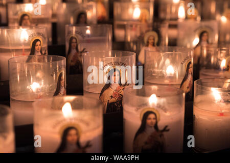 Righe di candele accese con santa Teresa di immagine sulla parte anteriore in Rouen Cathdral, Francia Foto Stock