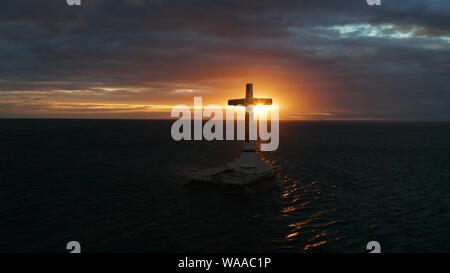 Croce cattolica nel cimitero affondata nel mare al tramonto, Vista aerea. Colorato nubi luminose durante il tramonto sul mare. Tramonto al cimitero affondata Camiguin Island Filippine. Foto Stock