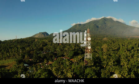 Antenne e microonde piatti di collegamento della rete di telefonia mobile e trasmettitore TV su torri di telecomunicazione con le montagne e la foresta pluviale. Camiguin, Filippine Foto Stock