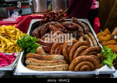 Assortimento diverse hot salsicce alla griglia e patate fritte cotte a tradizionale fiera di Natale Foto Stock
