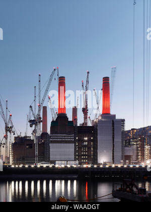 Vista stretto attraverso il Tamigi con illuminato sito di costruzione. Battersea Power Station 2019, Londra, Regno Unito. Architetto: vari, 2019. Foto Stock