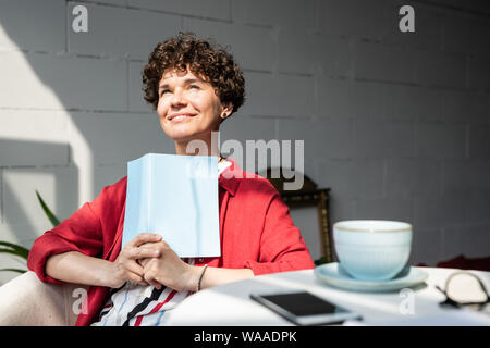Piuttosto giovane donna con libro aperto o il notebook sempre ispirato sulla giornata di sole Foto Stock
