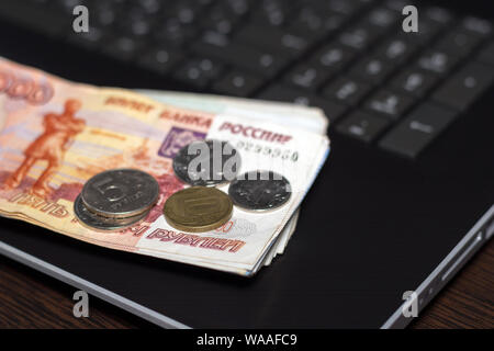 Raccontano di denaro. Contabilizzazione delle finanze. Vista ravvicinata di denaro russo, carta delle banconote e delle monete metalliche in euro i laici sulla tastiera del notebook. I salari in Russia concetto. Contanti Foto Stock