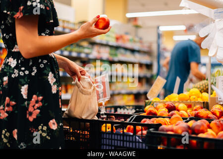 La donna si sceglie la frutta e la verdura al mercato alimentare. Eco riutilizzabile borsa per lo shopping Foto Stock