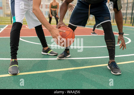 I giovani sportivi interculturale in activewear giocare a basket sulla corte esterna Foto Stock