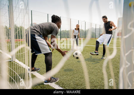 Giovane africana giocatore di calcio cattura la palla mentre il suo rivale di calcio Foto Stock