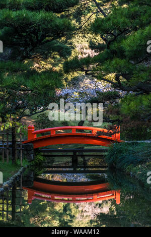 Un vivace ponte rosso e la sua riflessione al Giardino di Ritsurin a Shikoku, Giappone Foto Stock