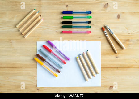 Vista della carta bianca e diversi insiemi di matite e penne e due pennelli Foto Stock