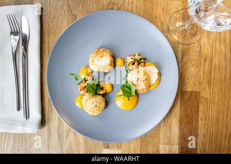 Colpo di pollo e gamberi con una verdura foglia su una piastra rotonda blu Foto Stock