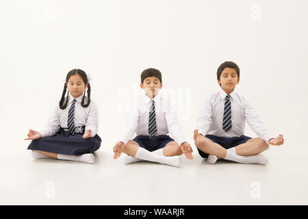 La scuola dei bambini seduti nella posa di yoga Foto Stock