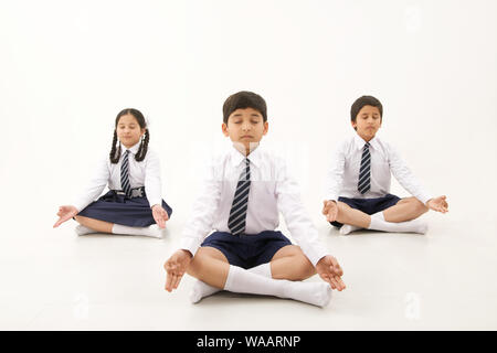 La scuola dei bambini seduti nella posa di yoga Foto Stock