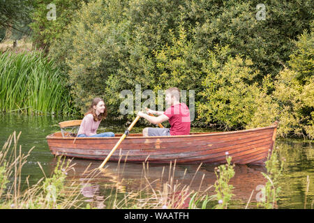 I visitatori di Flatford Mill noleggio barche a remi per esplorare il fiume Stour, Dedham Vale, Suffolk, Inghilterra, Regno Unito Foto Stock