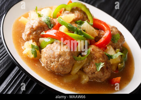 Le polpette di carne cotti con ananassi freschi e verdure in una salsa agrodolce closeup su una piastra sul tavolo orizzontale. Foto Stock