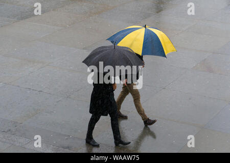 La gente camminare sotto la pioggia, Trafalgar Square, Londra, Gran Bretagna. Foto Stock