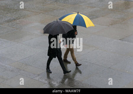 La gente camminare sotto la pioggia, Trafalgar Square, Londra, Gran Bretagna. Foto Stock