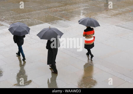 La gente camminare sotto la pioggia, Trafalgar Square, Londra, Gran Bretagna. Foto Stock