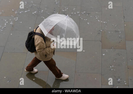 La gente camminare sotto la pioggia, Trafalgar Square, Londra, Gran Bretagna. Foto Stock