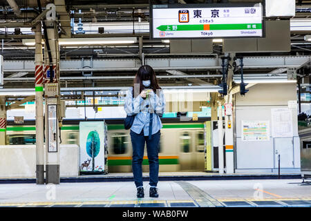 Giappone, Honshu, Tokyo, Stazione di Tokyo, Linea Yamanote piattaforma, giovane donna con maschera in attesa del treno, 30076250 Foto Stock