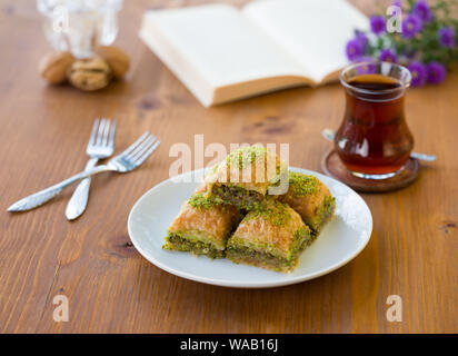 Il baklava tradizionale con tè turco sul tavolo di legno Foto Stock