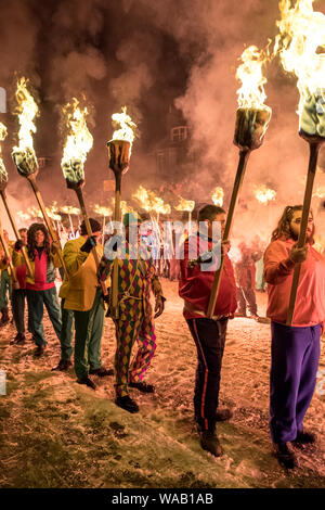 Gli uomini in un colorato abiti fantasiosi costumi sfilano per le strade innevate di Lerwick portando torce di fuoco al 2019 Up Helly Aa festival in Shetland Foto Stock