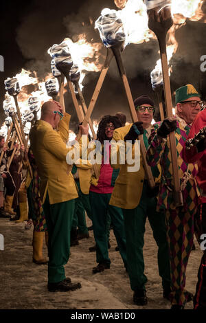 Gli uomini in abiti fantasiosi portando torce di fuoco al fino di Helly Aa festival a Lerwick, Shetland Foto Stock