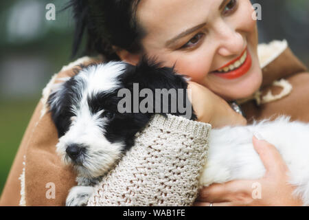 Donna che mantiene e abbracciando il suo nuovo cucciolo, vicino il fuoco selettivo Foto Stock