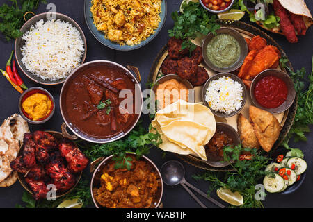 Vari piatti indiani dotate di rogan josh, pollo tikka masala, biryani, pollo tandoori, Spiedini misti e piatto indiano con samosa, pakoras, su Foto Stock