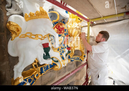 Colin Morris, da Nevin di pittori di Edimburgo, si applica la foglia di oro a uno dei royal stemmi durante i lavori di ristrutturazione sulla facciata principale di Canongate Kirk di Edimburgo. Foto Stock