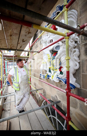 Colin Morris, da Nevin di pittori di Edimburgo, vernici uno dei royal stemmi durante i lavori di ristrutturazione sulla facciata principale di Canongate Kirk di Edimburgo. Foto Stock