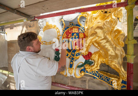 Colin Morris, da Nevin di pittori di Edimburgo, si applica la foglia di oro a uno dei royal stemmi durante i lavori di ristrutturazione sulla facciata principale di Canongate Kirk di Edimburgo. Foto Stock