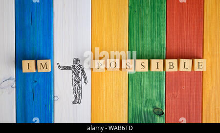 Disegnata a mano la silhouette di un uomo che fa un gesto di arresto per allontanare le lettere IM dalla parola impossibile in una immagine concettuale. Oltre in legno colorato indietro Foto Stock