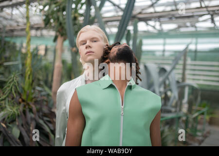 Uomo con dreadlocks appoggiato sullo spallamento del biondo uomo Foto Stock