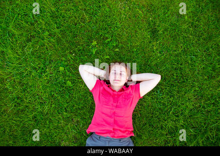 Ritratto di un sorridente i Capelli rossi ragazza sul prato verde. Il riposo e il relax del concetto. Foto Stock