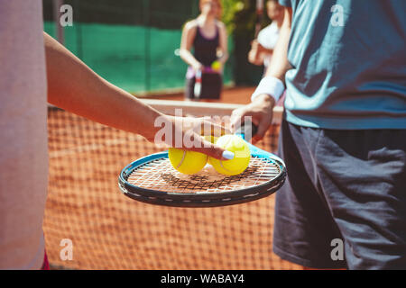 Close-up di un giovane giocatore di tennis prima di servire al match di tennis su outdoor clay court. Messa a fuoco selettiva. Messa a fuoco su un mani che tenendo palla e racchetta Foto Stock