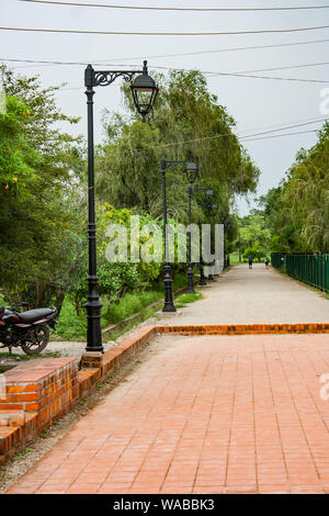 Strada lastricata in mattoni con lampione all'interno del Giardino Lumbini, luogo di nascita del Buddha di Gautam. Foto Stock