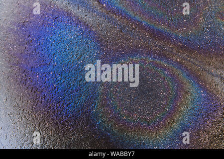 Iridato benzina posto su un pavimento bagnato. Ambiente di sfondo dell'inquinamento. Un disastro ecologico astratta. Foto Stock